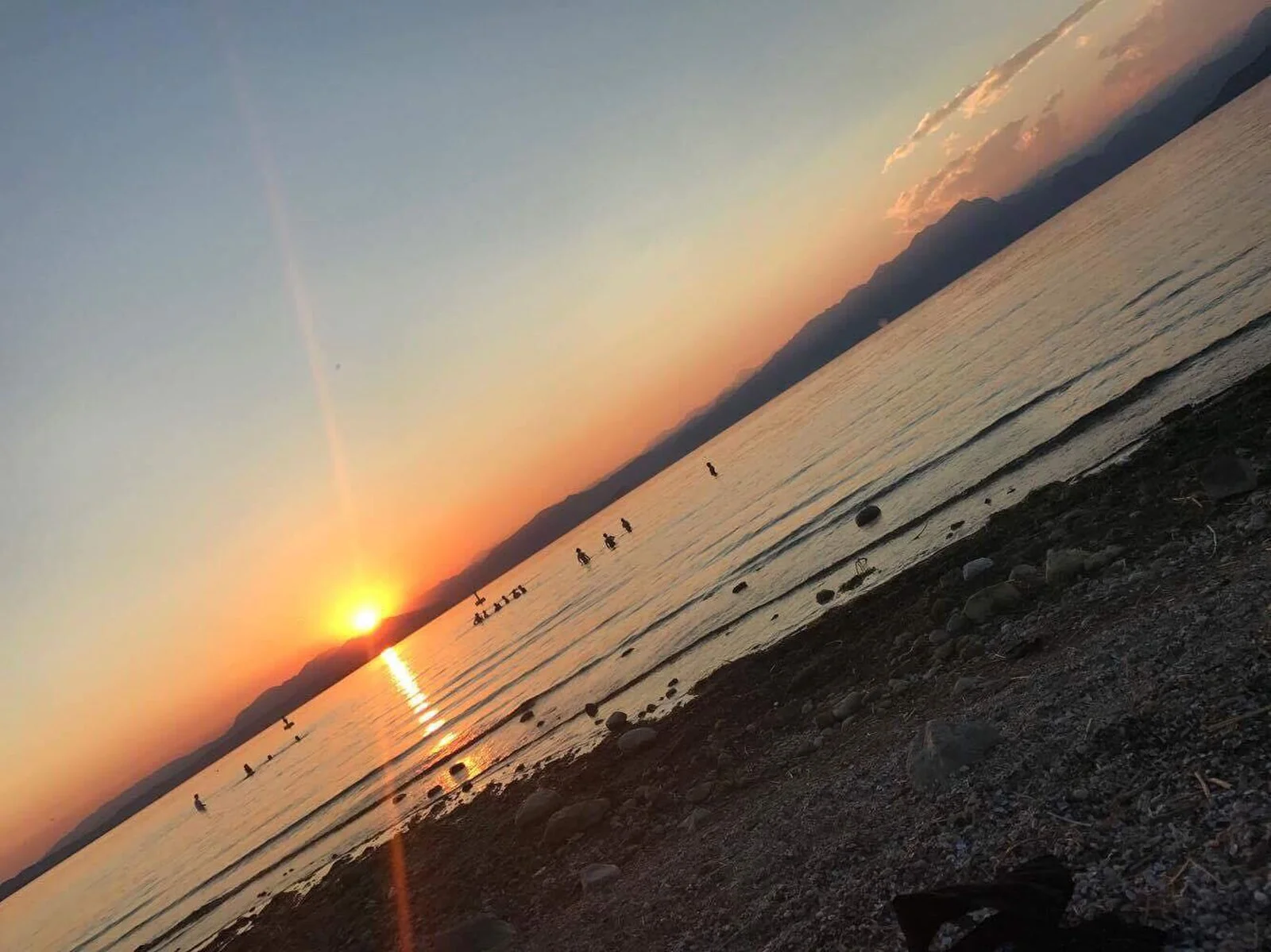 Kiezelstrand aan het Gardameer met helder water en bergen op de achtergrond